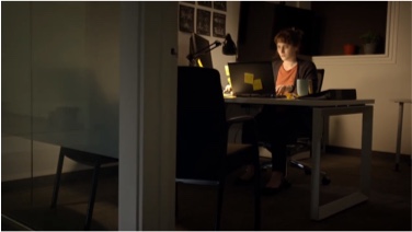 Woman works at computer at office at night